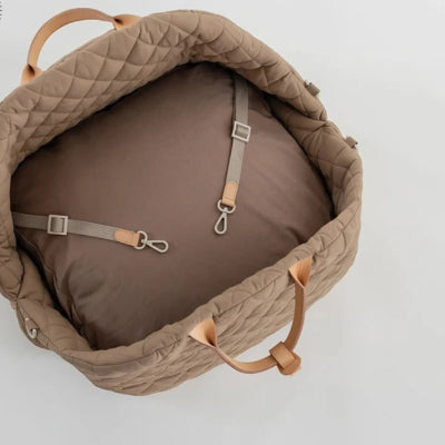 sac de transport pour chien brun avec coussin et crochets internes ouvert sur sol blanc