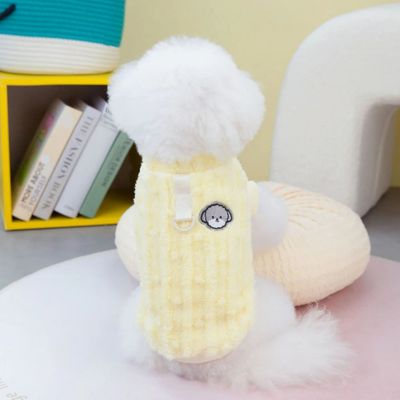 caniche blanc assis sur tapis porte vetement pour chien jaune